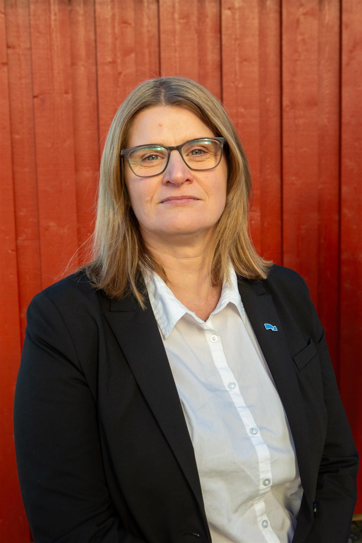 Portrett av dame foran rød vegg. - Klikk for stort bilde