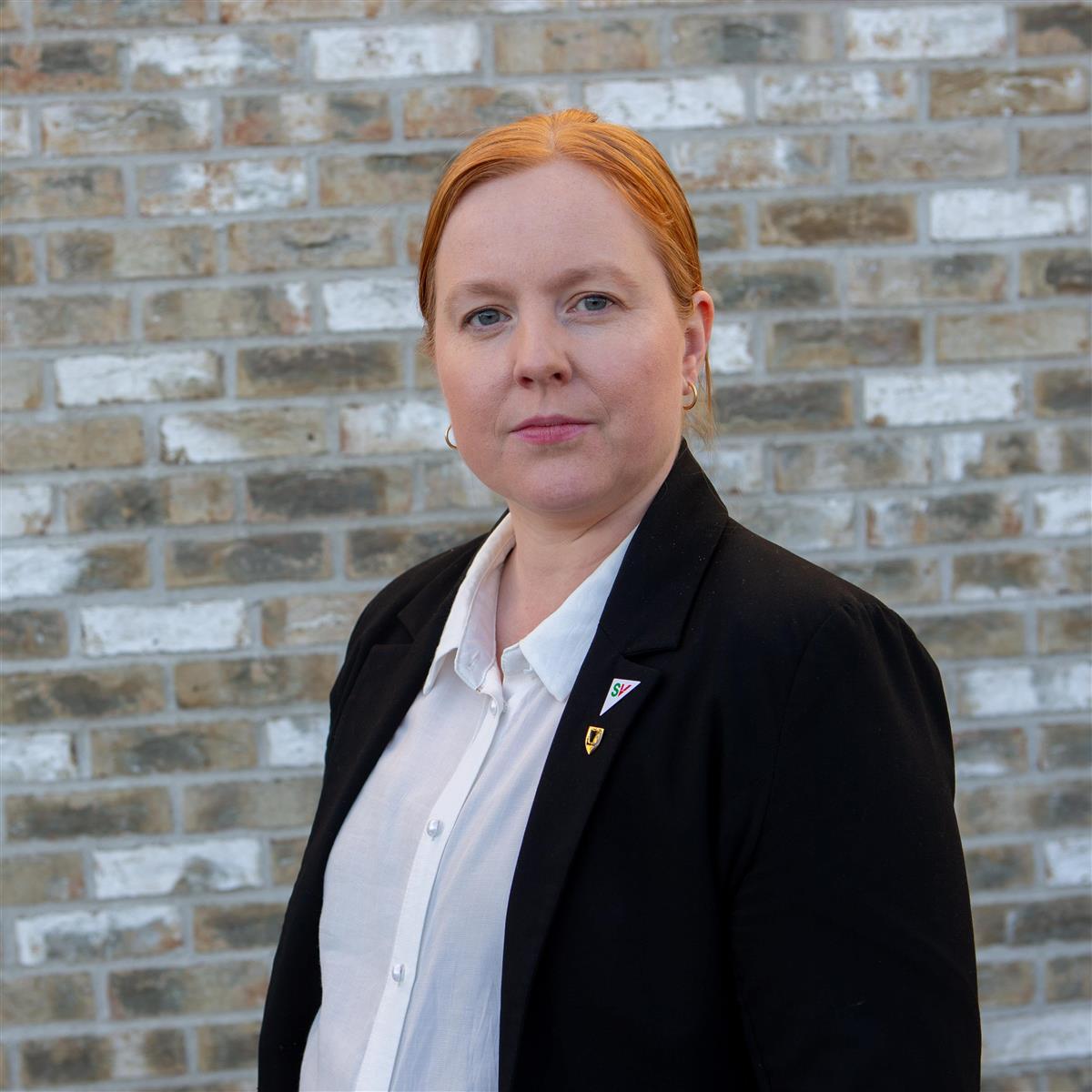 Kvinne foran murvegg. Foto. - Klikk for stort bilde