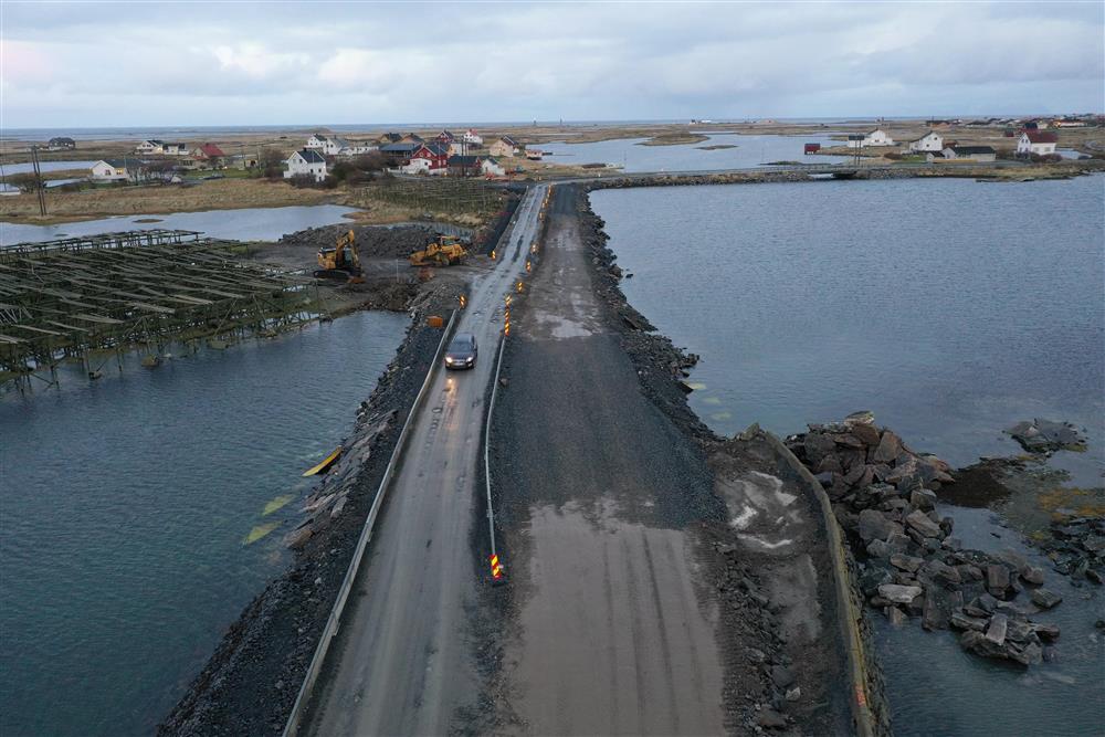 Lav bru over sund, noe anlegsaktivitet og skilting, boliger og fjord i bakgrunnen. Dronefoto - Klikk for stort bilde