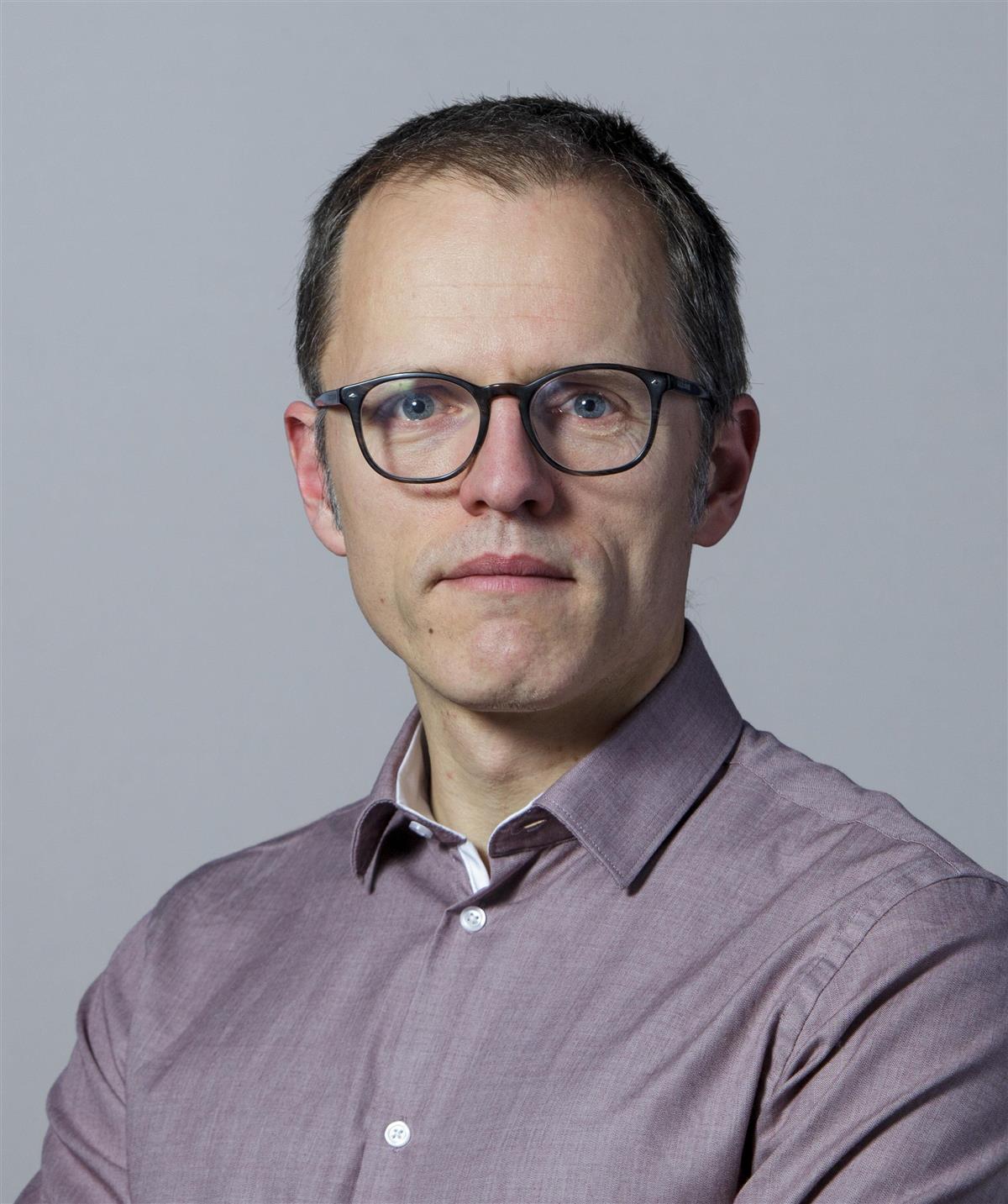 Portrett av mann med briller og grå skjorte - Klikk for stort bilde