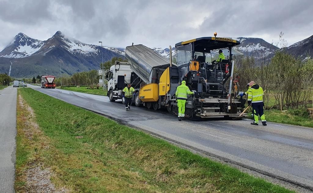 Asfaltering på veg, fjell med noe snø i bakgrunnen. - Klikk for stort bilde