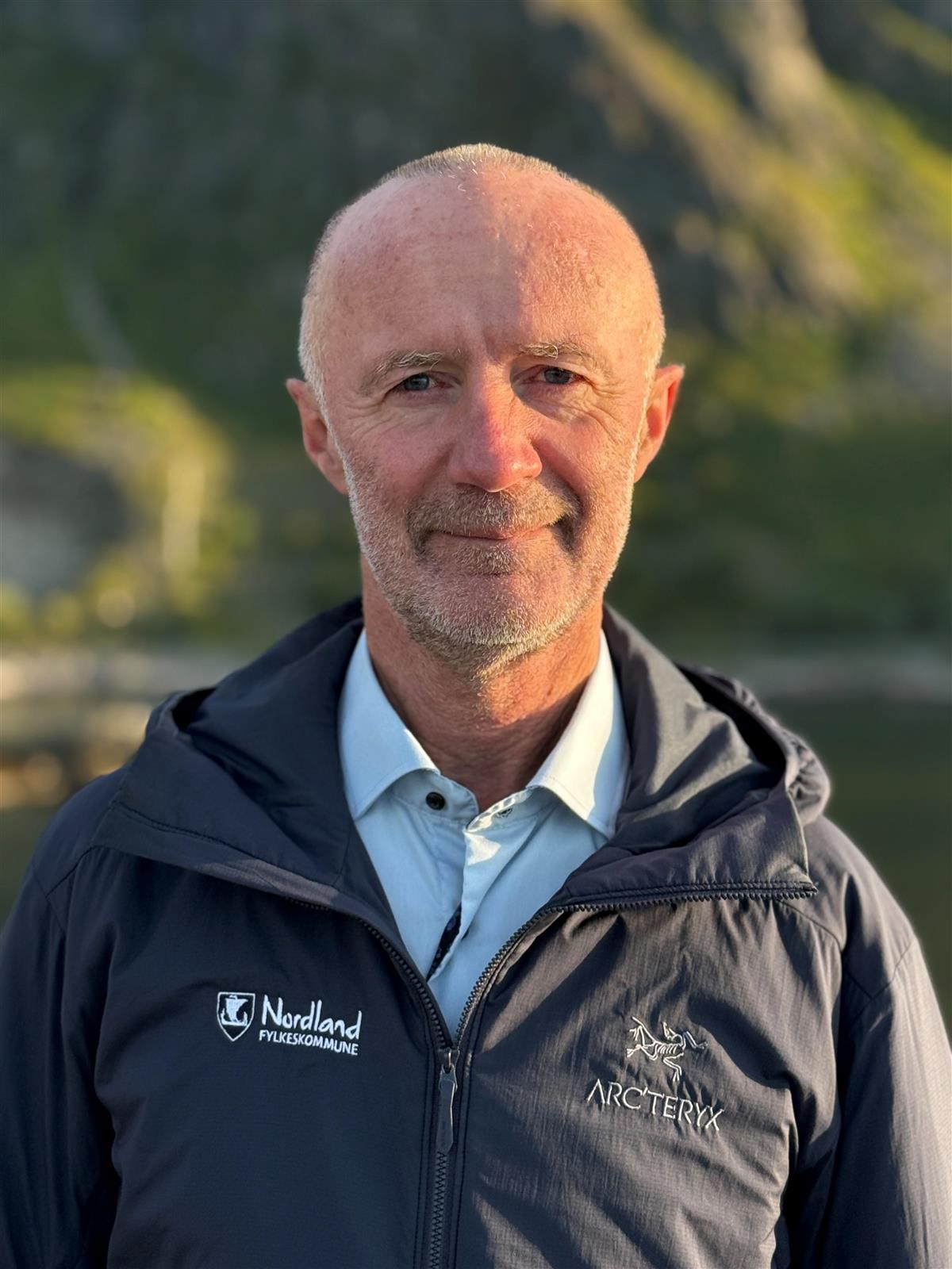 Portrett av mann i sollys. Fjell i bakgrunne. - Klikk for stort bilde