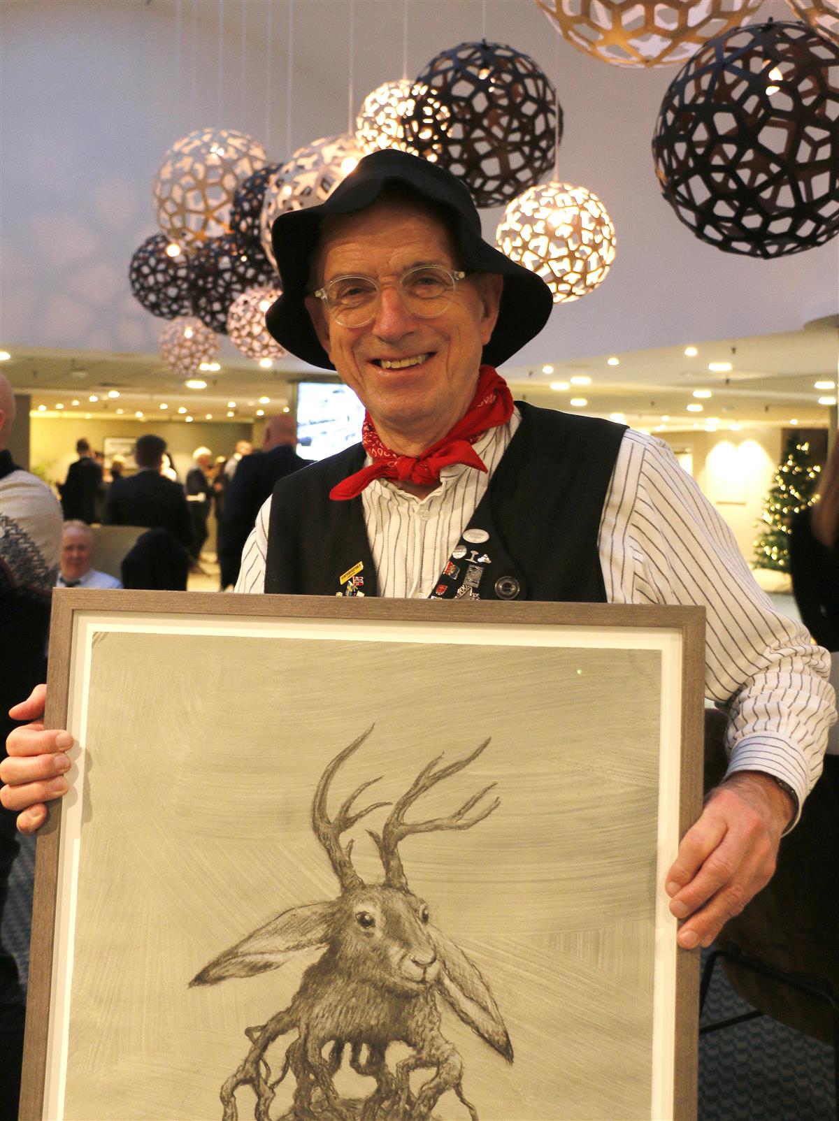 Smilende mann i rallarhatt som holder et innrammet bilde. Foto - Klikk for stort bilde