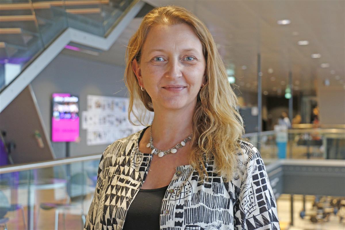 Smilende kvinne i et stort rom. Foto. - Klikk for stort bilde