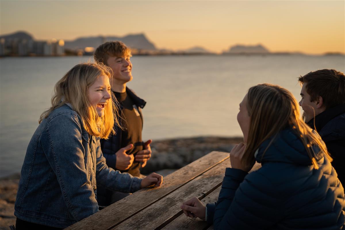 Fire ungdommer samlet rundt et bord på moloen i Bodø - Klikk for stort bilde
