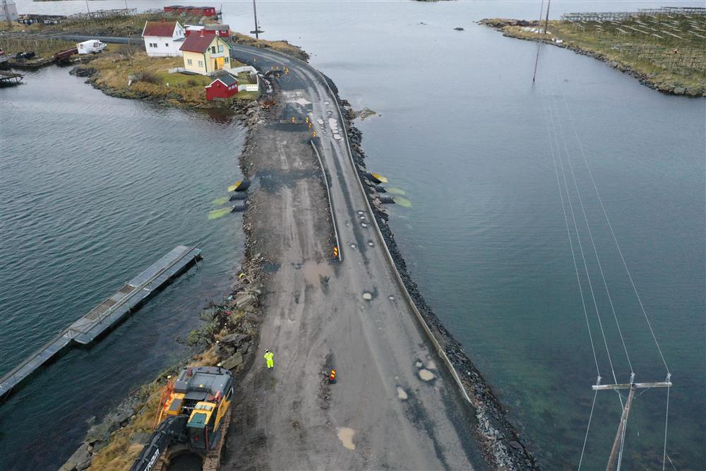 Lav bru over sund, noe anlegsaktivitet og skilting, boliger og fjord i bakgrunnen. Dronefoto - Klikk for stort bilde
