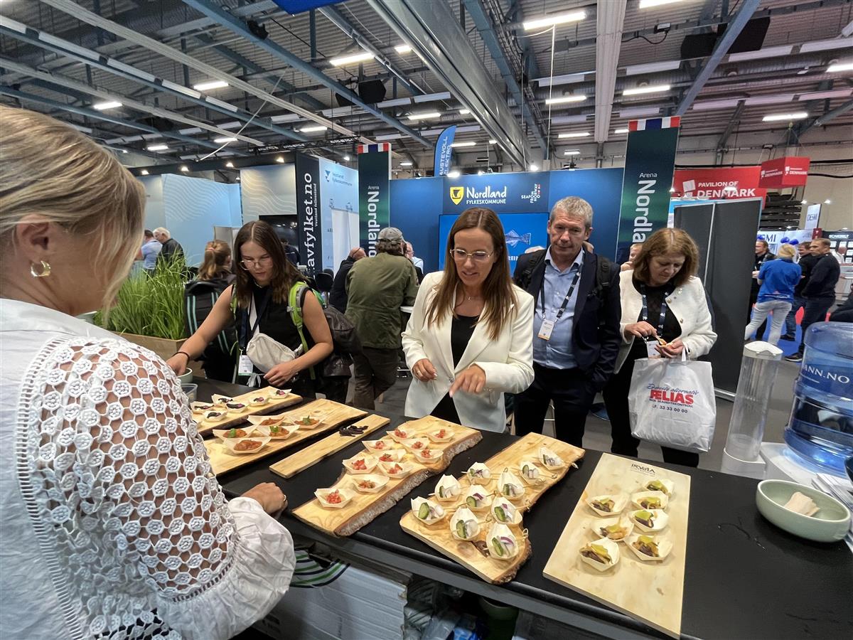 Personer som står foran et bord med mat i en messehall. Foto. - Klikk for stort bilde