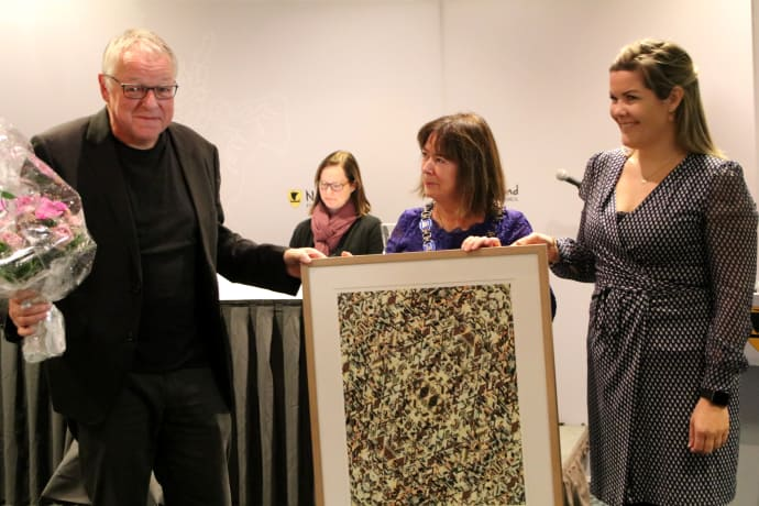 Mann med kunstbilde ig blomster, samen med tre kvinner. Foto. - Klikk for stort bilde