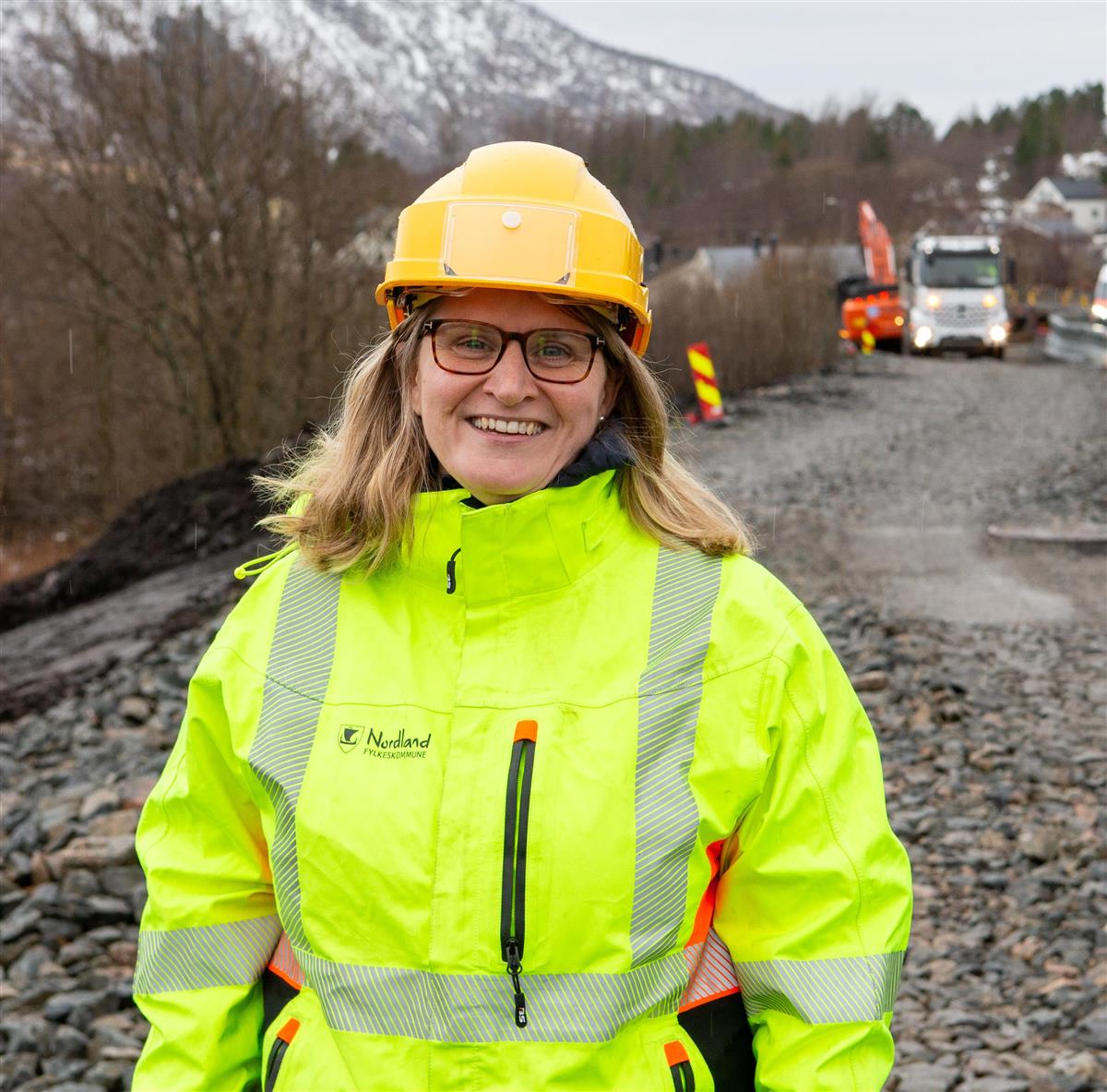 Dame kledd i gule arbeidsklær på gang- og sykkelvei under bygging. - Klikk for stort bilde