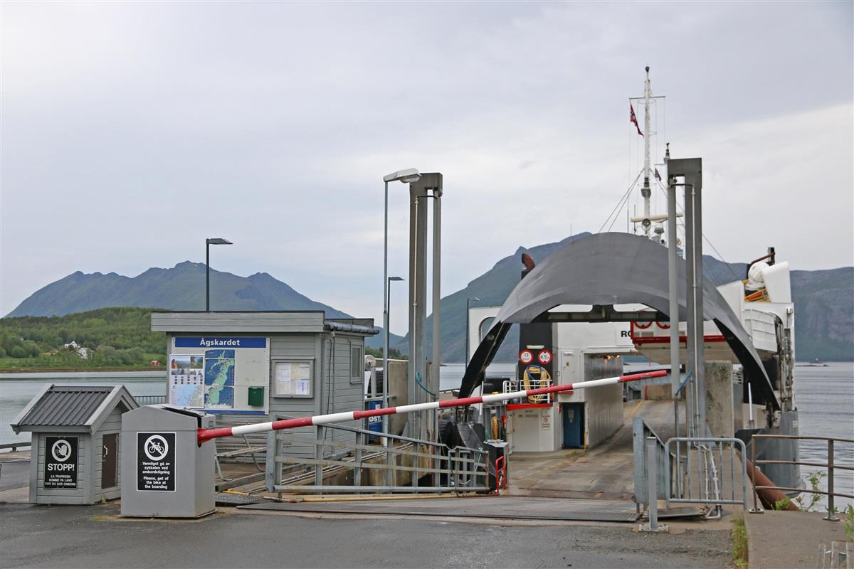 Ferge ligger til kai på Ågskardet. Bommen er halvveis oppe/nede. Grønne åser og fjell i bakgrunnen. Foto - Klikk for stort bilde