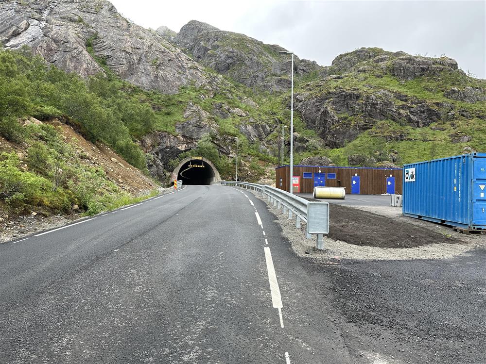 Veg mot tunnel, bygg og brakke utenfor - Klikk for stort bilde