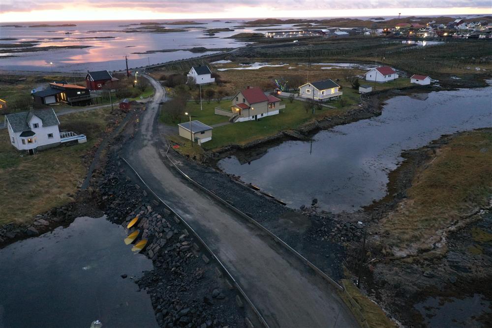 Lav bru over sund, boliger og fjord i bakgrunnen. Dronefoto - Klikk for stort bilde