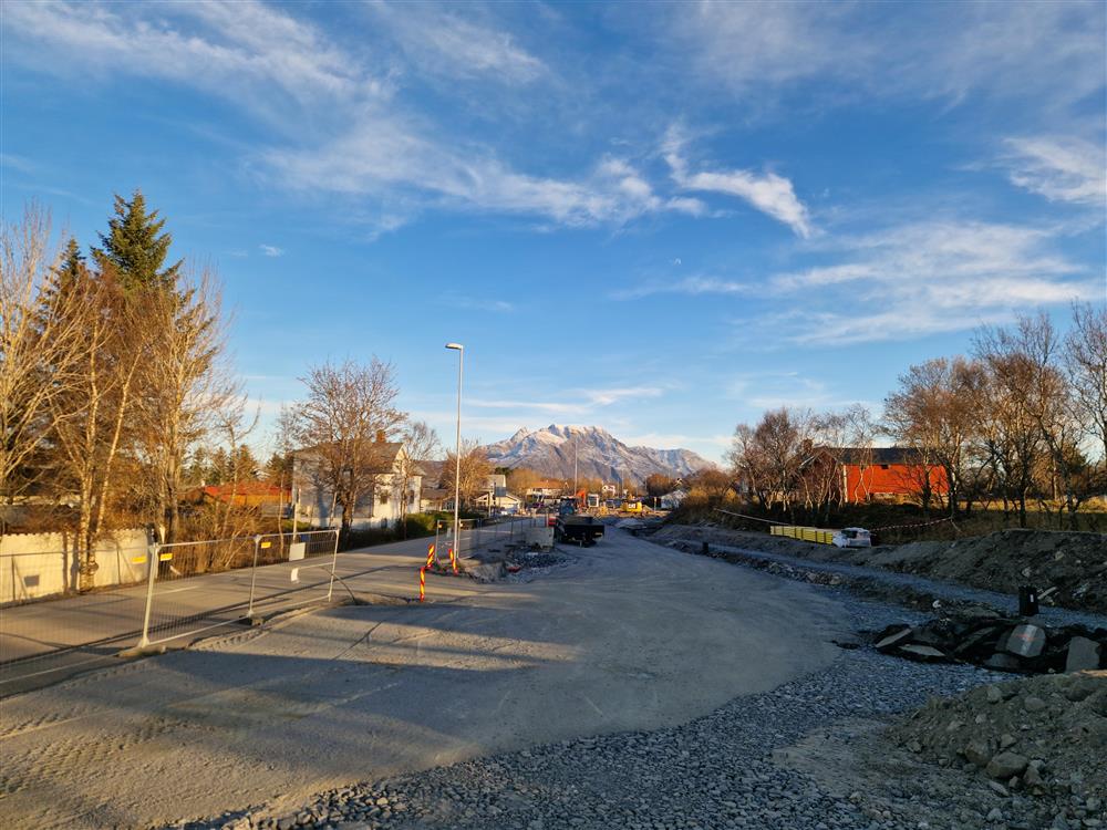 vegarbeid, avsperret område, skilt, bygninger. Fjell med litt snø i bakgrunnen. Foto.  - Klikk for stort bilde