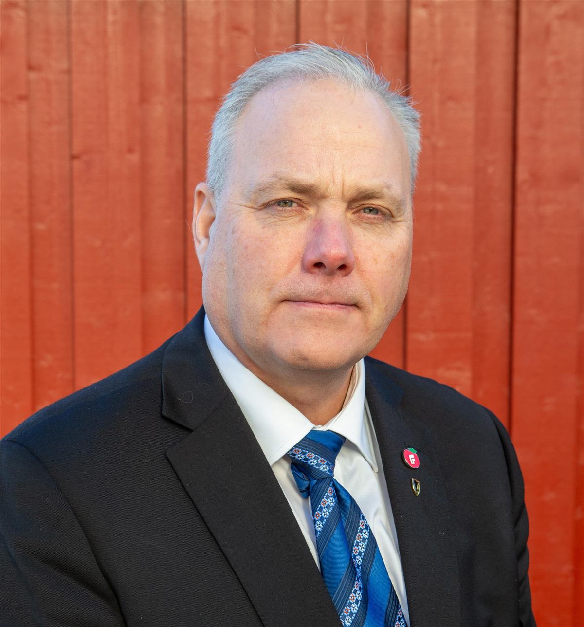 Alvorlig mann med rød vegg som bakgrunn.Foto. - Klikk for stort bilde